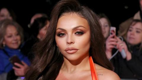 Jesy Nelson, former member of Little Mix, with long dark hair, behind her are fans with mobile phones raised. She is attending the National Television Awards 2020.