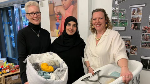 Prof Sally Pearse of Sheffield Hallam University (left, wearing a black jumper and holding a basket of coloured blankets), Lina Mohsen, a mum who has benefited from the scheme (middle, wearing a black hijab), and Cat Ross, Baby Basics chief executive (right, wearing a white top and holding a moses basket).