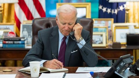 President Joe Biden talks on the phone in the Oval Office