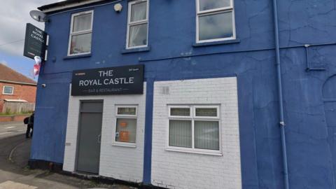 The exterior of a pub, painted blue. A sign says The Royal Castle bar and restaurant