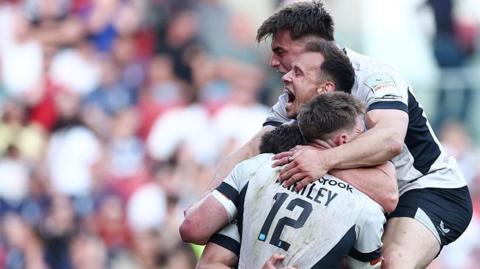 Tobias Elliott yells in delight as he hugs his team-mates in celebration of scoring a late try to seal their win over Bristol.