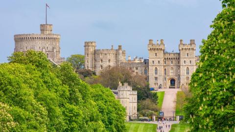 A general view picture of Windsor Castle, with the entrance gates and people stood outside them at the bottom of the picture.