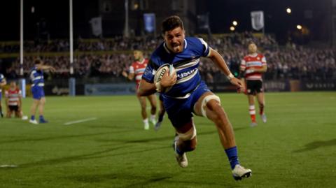 Ewan Richards of Bath sticks his tongue out as he runs unchallenged towards the camera to score a try as Bath play Gloucester at the Rec.