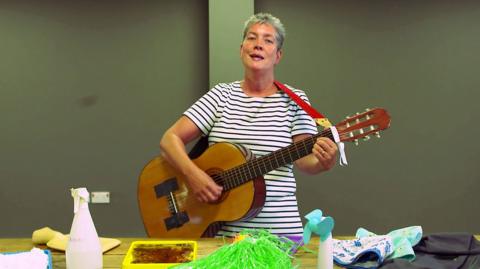 A lady is playing the guitar and singing