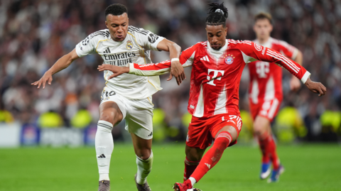  Michael Olise of FC Bayern Munich is challenged by Kylian Mbappe of Real Madrid