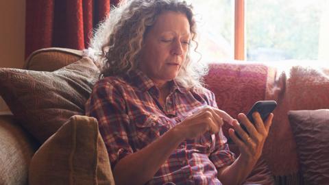 Woman using phone on the sofa