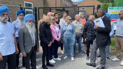 Residents in front of security fences at Edward Moore House 