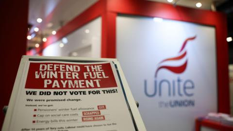 A leaflet in the foreground says "Defend the winter fuel payment - we did not vote for this", with a sign that read "Unite the Union" in the background 