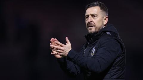 Port Vale manager Jon Brady claps the crowd after a game 