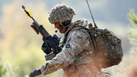 Profile view of a British Army soldier training in battle dress and a rifle