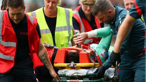 Wrexham goalkeeper Danny Ward is carried off injured at Millwall
