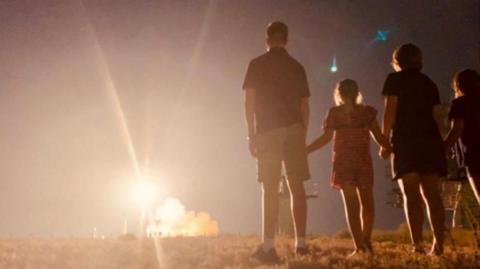 People watching a rocket launch in the distance