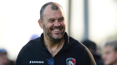 Michael Cheika smiles while walking past Leicester Tigers fans