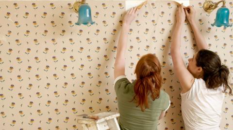 Two women stripping wallpaper