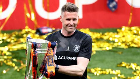 Rob Edwards holding the play-off final trophy at Wembley after success with Luton in 2023