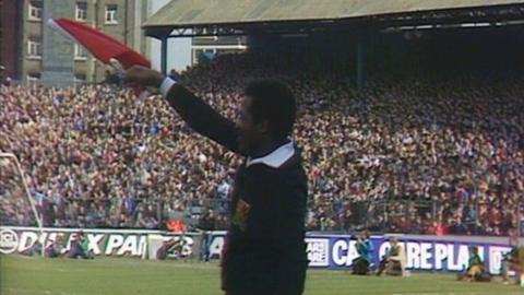 Emerson Griffiths waving a red flag on the pitch in an old photo