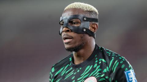 Victor Osimhen wearing a black protective face mask and a green and black Nigeria shirt