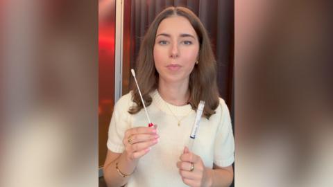 A woman holds up an HPV testing kit.