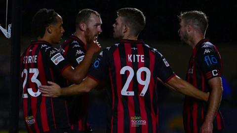 Four Truro City players stand together to celebrate a goal