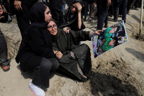 A woman holding a picture of children during funeral for victims following Israeli strike