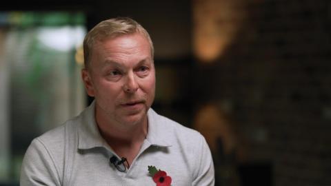 Sir Chris Hoy wearing a grey polo shirt and poppy speaks to the BBC