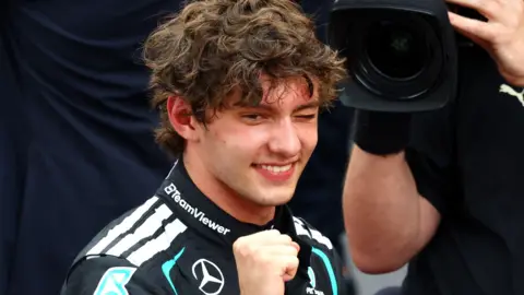 Kimi Antonelli clenches his fist, winks and smiles in celebration after winning the Monaco Grand Prix