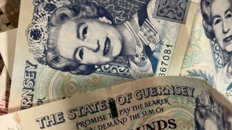 A close-up of bank notes. At the top it has the words The States of Guernsey.