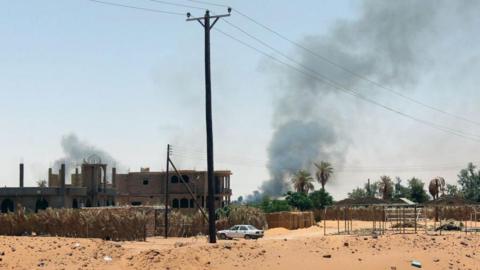 Black smoke billows as fighting takes place in Kufra, Libya, in June 2012