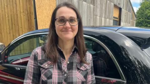 Claire Barrows in front of her electric car which was damaged by a pothole