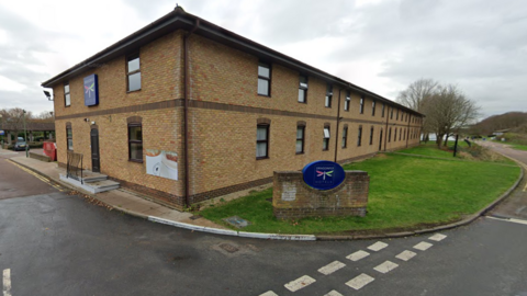 The exterior of the Dragonfly Hotel. It is a brick building and is two-storey. There is grass and a road outside