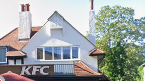 Close-up of KFC branch in West Wickham, showing the gable roof and top windows, as well as chimneys of the building