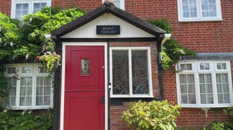 A red brick house with a red front door.