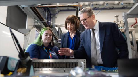 A young female worker shows Chancellor Rachel Reeves and Prime Minister Keir Starmer products at the PsiQuantum premises in Daresbury