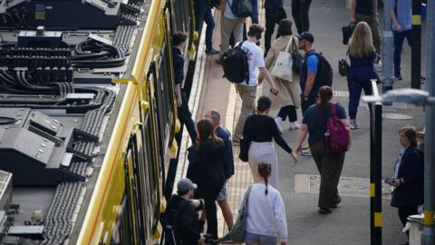 Commuters on a platform leave a Northern train on to a platform. 