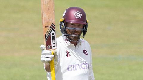 Luke Procter raises his bat during an innings for Northamptonshire