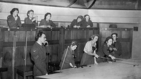 Men and women in uniform at work in operations room