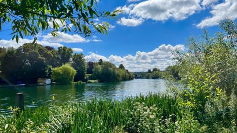 SUNDAY - A river at Cookham with green banks and the sun shining in a blue sky