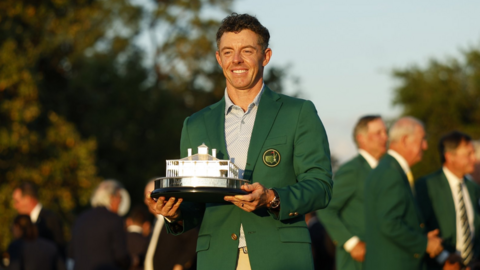 Rory McIlroy, a man wearing a green jacket and holding a silver trophy for winning the Masters in Augusta.