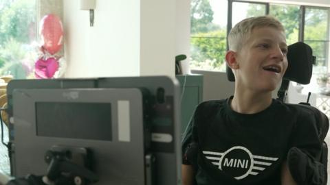 Boy with blond hair and black-shirt sitting in front of computer screen