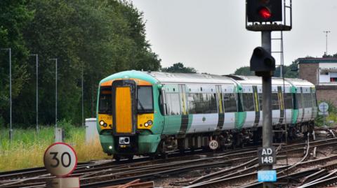 A white, green and yellow train moving on railway tracks. 