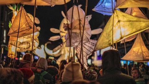 Crowds of people carrying lanterns in the street.