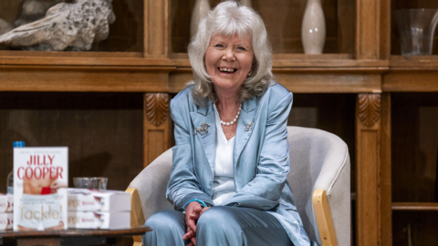 Dame Jilly Cooper wearing a blue satin suit