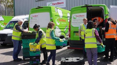 Volunteers for FareShare Sussex & Surrey carrying crates of food into vans.