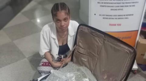 Taylor Tamara Simone, 21, sat on the floor in the Robert Gabriel Mugabe International Airport. She is next to a large white suitcase that's filled with packets that contained the cannabis. 