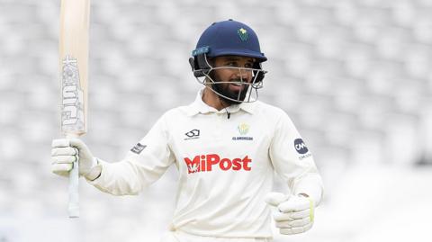 Zain ul Hassan raises his bat with his right hand to acknowledge scoring his hundred against Hampshire