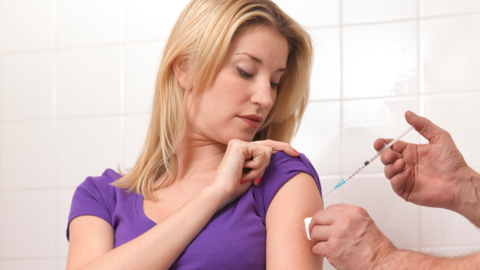 Stylised photo of a flu jab being given to woman patient with the needle about to into her arm. 