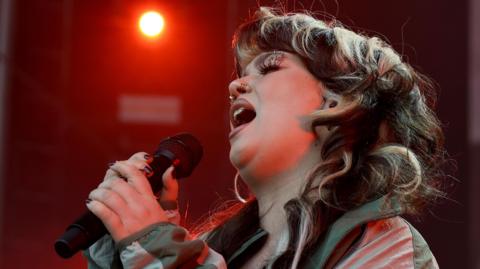 Lola Young singing on stage