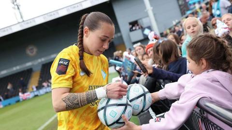 London City Lionesses goalkeeper Elene Lete signs a ball for a young fan after a match