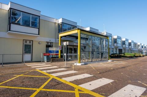 Front view of Queen Elizabeth Hospital in King's Lynn. On the road in front are lots of markings indicating that vehicles shouldn't stop