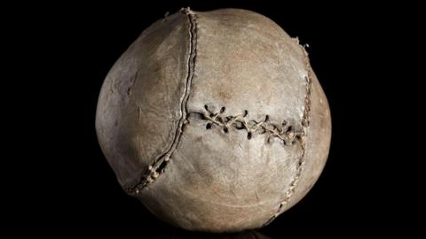 An almost 500-year-old football on display. It has thick stitching across its surface.